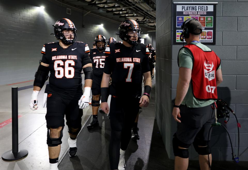 Oklahoma State's Joe Michalski (66) and Alan Bowman (7) walk to the field for warm ups before the Big 12 Football Championship game between the Oklahoma State University Cowboys and the Texas Longhorns at the AT&T Stadium in Arlington, Texas, Saturday, Dec. 2, 2023.