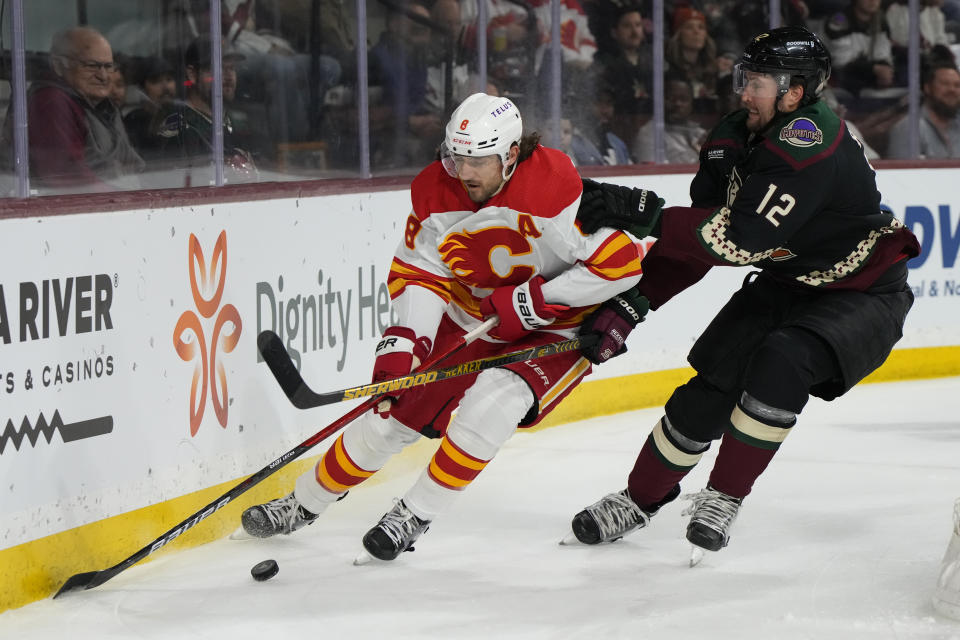 Calgary Flames defenseman Chris Tanev (8) shields the puck from Arizona Coyotes left wing Nick Ritchie during the first period during an NHL hockey game Wednesday, Feb. 22, 2023, in Tempe, Ariz. (AP Photo/Rick Scuteri)