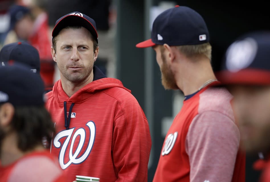 Washington Nationals pitcher Max Scherzer (left) chats with teammate Stephen Strasburg in the dugout during a game in 2017. (AP)