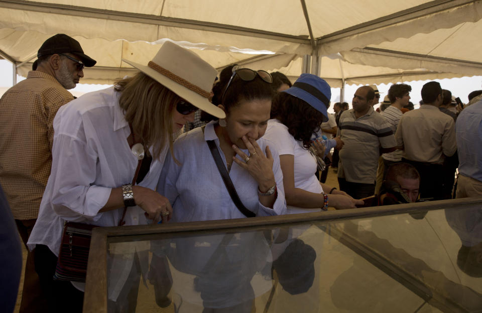 Women look at recently discovered artifacts at the Bent Pyramid during an event opening the pyramid and its satellites for visitors in Dashur, Egypt, Saturday, July 13, 2019. An Egyptian mission led by Dr. Mostafa Waziri discovered a collection of stone, clay and wooden sarcophagi which some of it still houses its mummies in addition to wooden funerary masks and instruments used in cutting stones from the Late period. (AP Photo/Maya Alleruzzo)