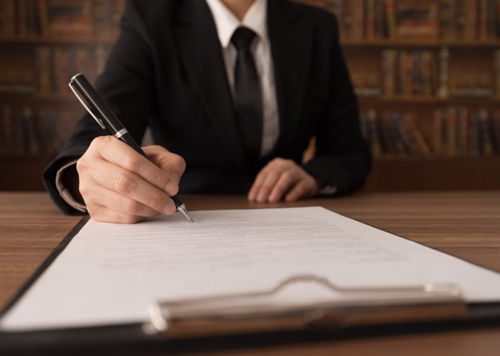 A close up of a person signing a piece of paper.