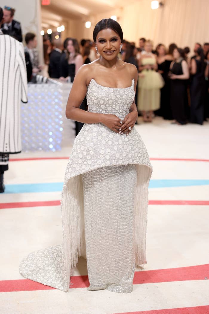 Mindy smiles on the Met Gala red carpet in Jonathan Simkhai strapless hi-lodress with an exaggerated waist and long underskirt
