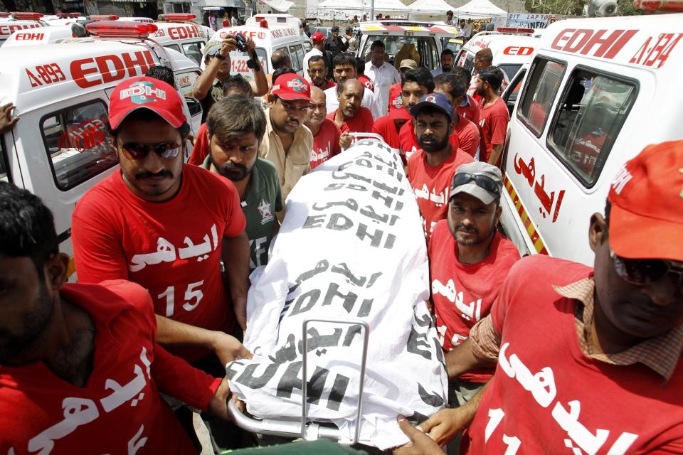 Pakistani volunteers carry a body of a bomb attack victim in Karachi Thursday, April 24, 2014. A Pakistani official says a bombing in the country's south targeted a police officer known for his anti-militant campaigns, killing him and his two friends. (AP Photo/Fareed Khan)