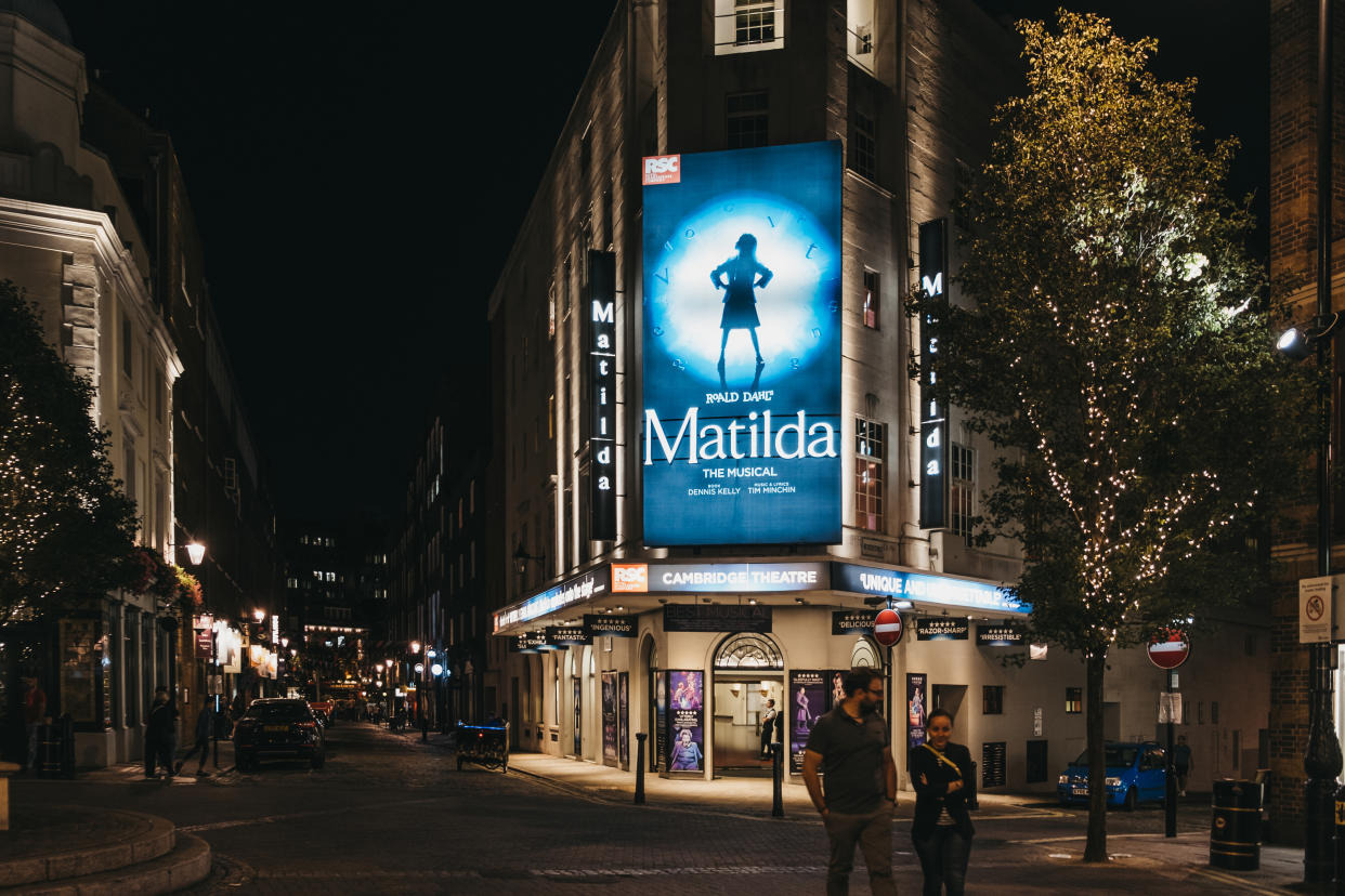 London, United Kingdom - August 31, 2019: Illuminated facade of Cambirdge Theatre located on Seven Dials, London, showing Matilda musical, at night, people walking in front, selective focus.