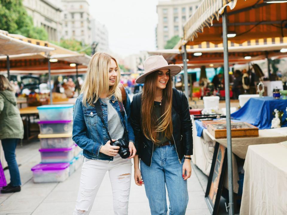 Two women walk through a flea market.