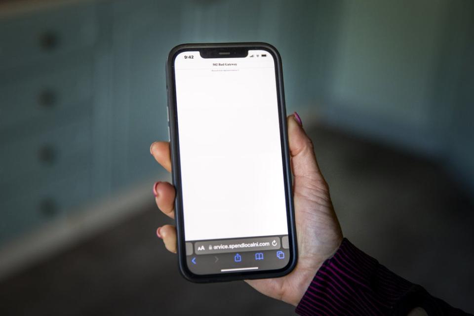 A woman using a mobile phone showing an error message after attempting to open a link to the High Street voucher scheme pre-paid card on the NI Direct website (Liam McBurney/PA) (PA Wire)