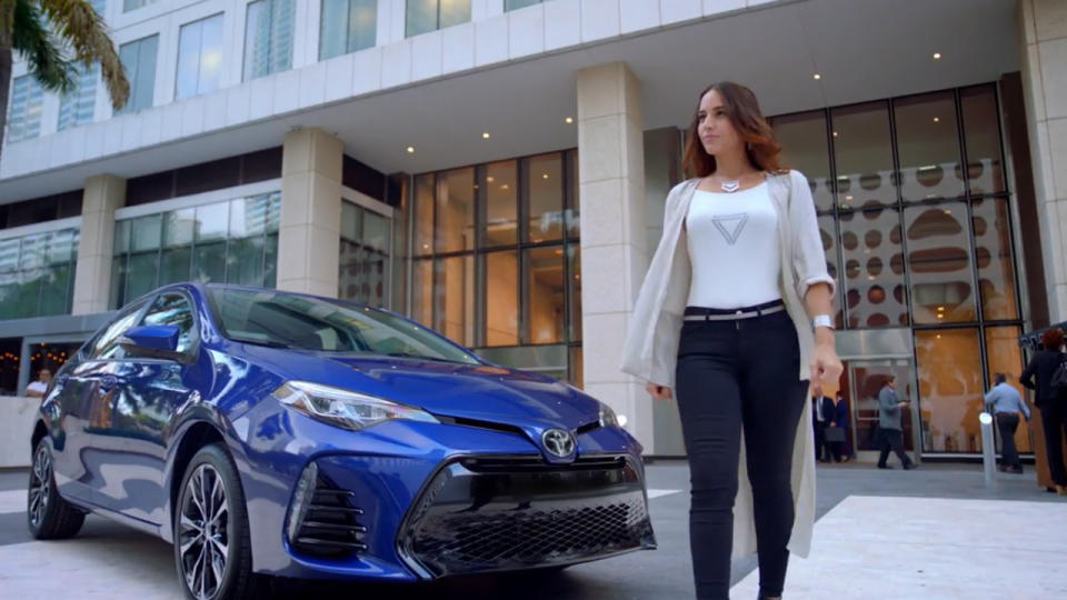 A model walking in front of a showroom vehicle.