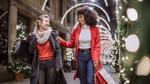 Pretty Young Female Friends Smiling Broadly In Cheerful Manner Having Fun At Shopping Mall, Buying Christmas Gifts