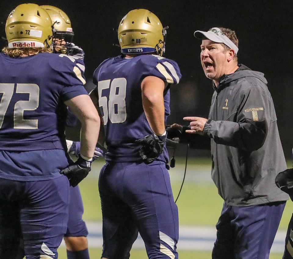 Hoban coach Tim Tyrrell talks with offensive linemen during a timeout in a game against St. Edward on Friday in Akron.