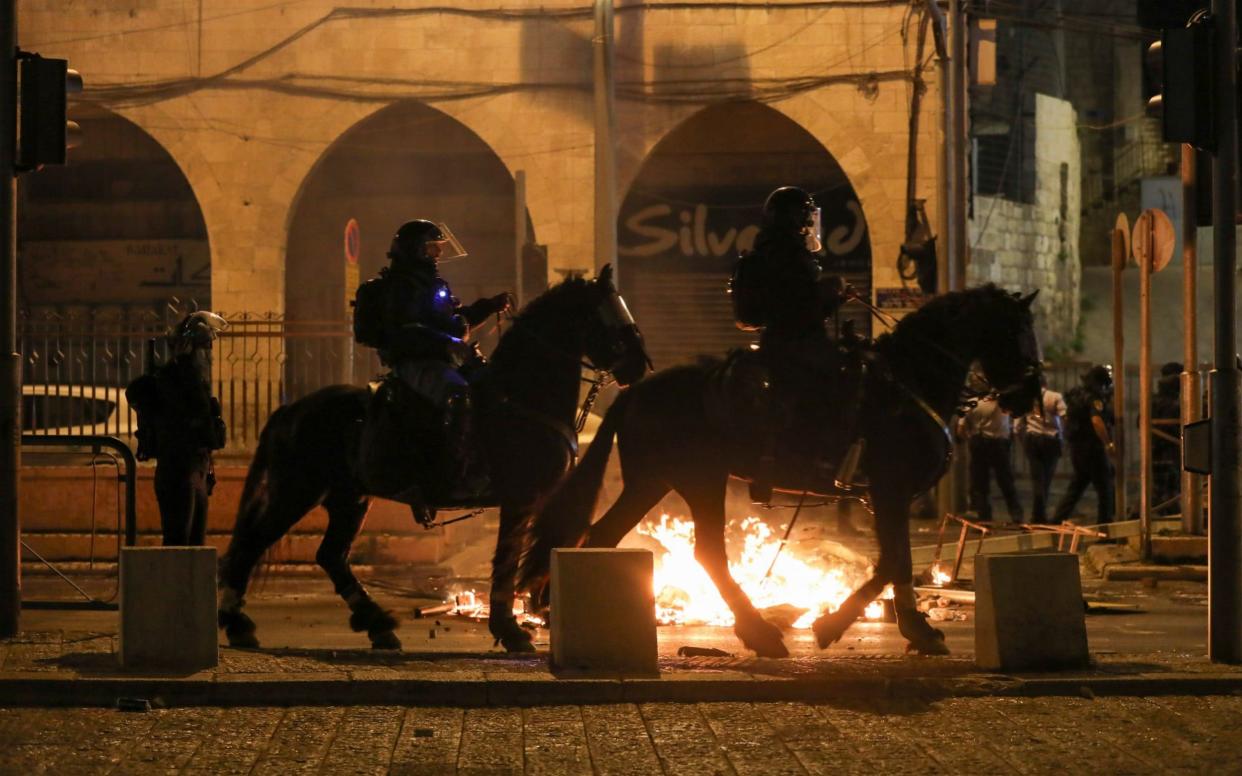 Mounted Israeli police officers ride past a fire during clashes with Palestinians, as the Muslim holy fasting month of Ramadan continues, in Jerusalem - Reuters/Reuters