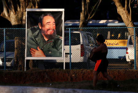 A woman walks past a photograph of former President Fidel Castro after the announcement of his death, in Havana, Cuba, November 27, 2016. REUTERS/Stringer