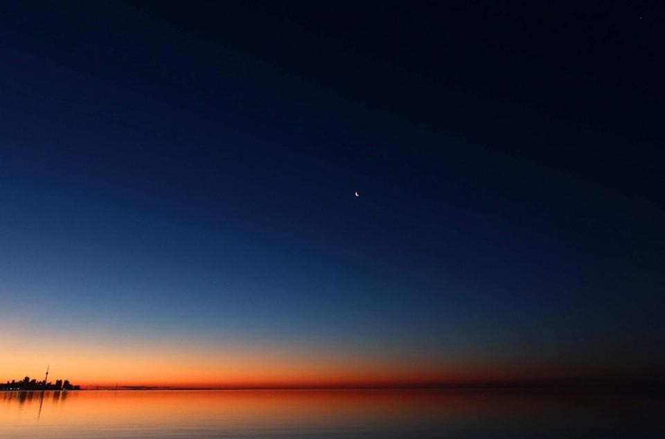 PHOTO: In this June 24, 2022, file photo, a crescent moon rises along with planets Venus, Mars and Jupiter above the CN Tower as the sun rises in Toronto, Ontario.  (Gary Hershorn/Corbis via Getty Images, FILE)