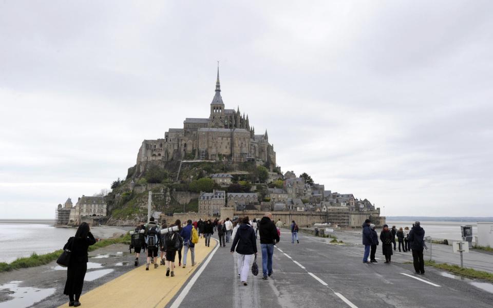 Tourists walk to the Mont-Saint-Michel, a French landmark and UNESCO world heritage, northwestern France - DAMIEN MEYERDAMIEN/AFP