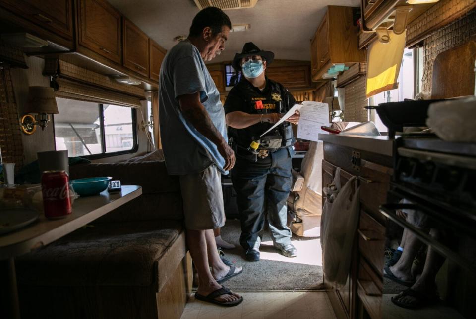 Maricopa County constable Darlene Martinez shows Hector Medrano court documents ordering his family’s eviction from an RV park on October 07, 2020 in Phoenix, Arizona. (Photo by John Moore/Getty Images)