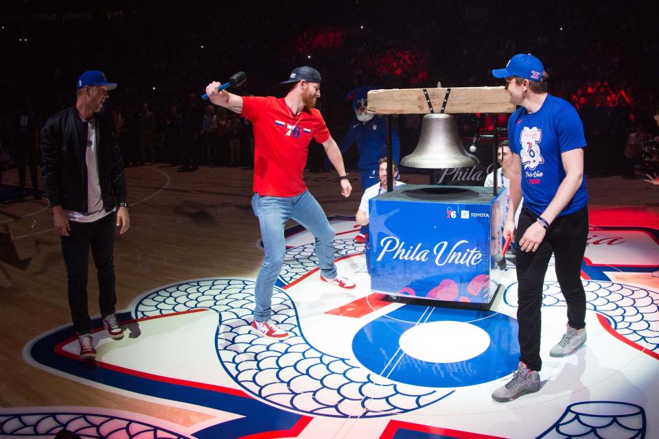 From left to right, the Philadelphia Phillies' Rhys Hoskins, the Philadelphia Eagles' Carson Wentz and the Philadelphia Flyers' James van Riemsdyk ring the bell before the start of a game between the Philadelphia 76ers and the Toronto Raptors in a 2019 NBA playoff game in Philadelphia.