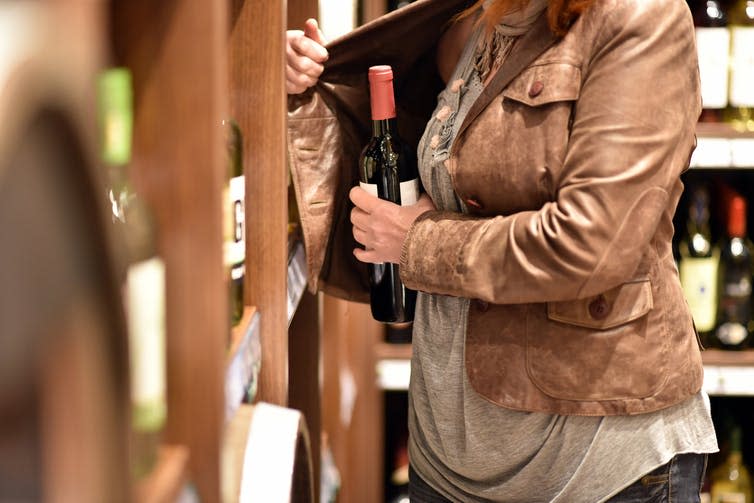 <span class="caption">Shop workers sometimes face violence when confronting shoplifters.</span> <span class="attribution"><a class="link " href="https://www.shutterstock.com/image-photo/shoplifting-woman-steals-bottle-wine-supermarket-1281358915?src=QpLU6UnuZvCEA1O2xccQsQ-1-0" rel="nofollow noopener" target="_blank" data-ylk="slk:Shutterstock;elm:context_link;itc:0;sec:content-canvas">Shutterstock</a></span>