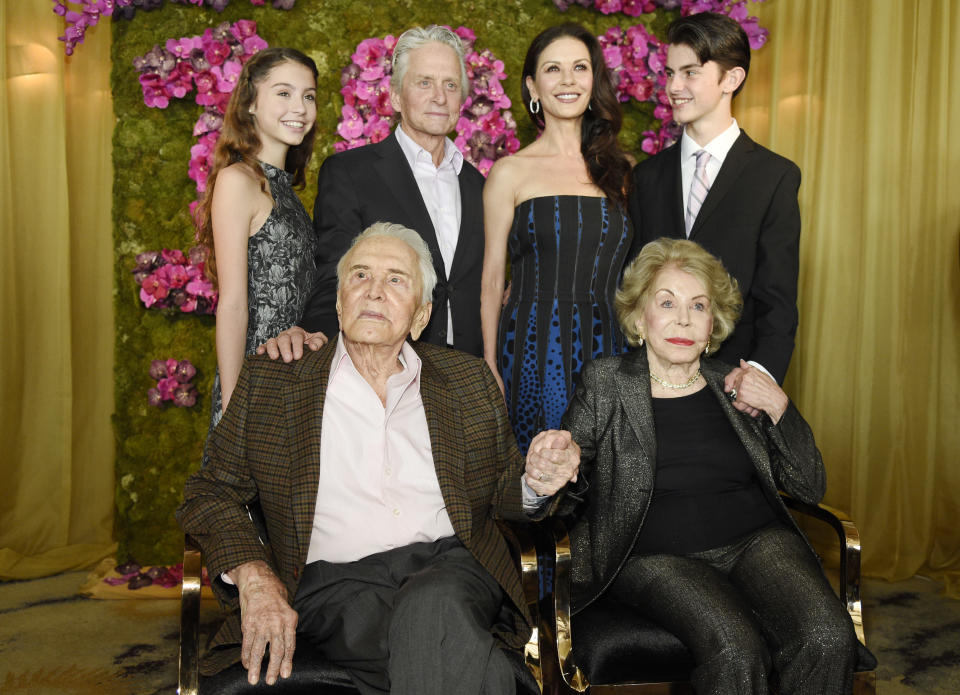 FILE - This Dec. 9, 2016 file photo shows actor Kirk Douglas, seated left, holding hands with his wife Anne Douglas, seated right, as they pose with family members, their son Michael, standing second left, his wife Catherine Zeta-Jones, standing second and their children, Carys, left, and son Dylan during Kirk's 100th birthday party in Beverly Hills, Calif. Kirk Douglas died Wednesday, Feb. 5, 2020 at age 103. (Photo by Chris Pizzello/Invision/AP)