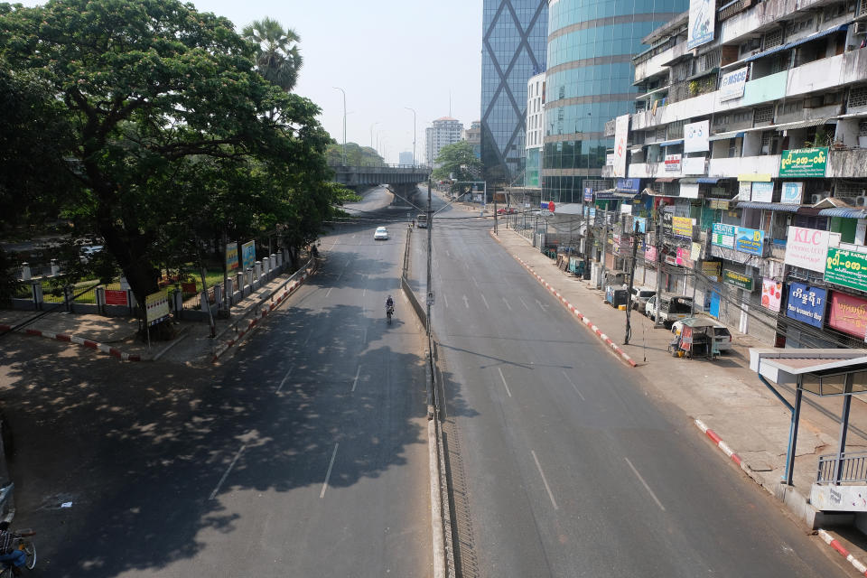 A biker and a car are seen on an almost empty road in Yangon, Myanmar Wednesday, March 24, 2021. Anti-coup protesters on Wednesday tried a new tactic that they dubbed a "silence" strike, calling for people to stay home and businesses to close for the day. (AP Photo)