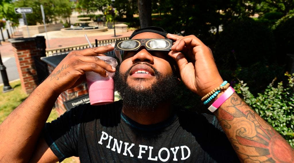 Frankie Page of Spartanburg puts on his glasses to look at the total solar eclipse Aug. 21 in downtown Spartanburg. [ALEX HICKS JR./SPARTANBURG HERALD-JOURNAL]