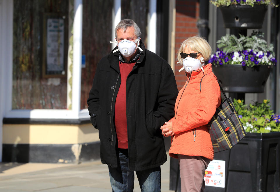 Members of the public wearing masks queue to enter shops in Melton Mowbray as the UK continues in lockdown to help curb the spread of the coronavirus.