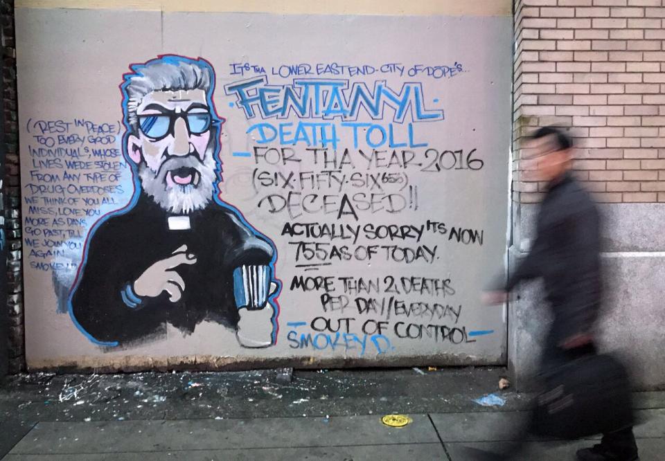 A man walks past a mural by street artist Smokey D. about the fentanyl and opioid overdose crisis, in the Downtown Eastside of Vancouver, B.C. 