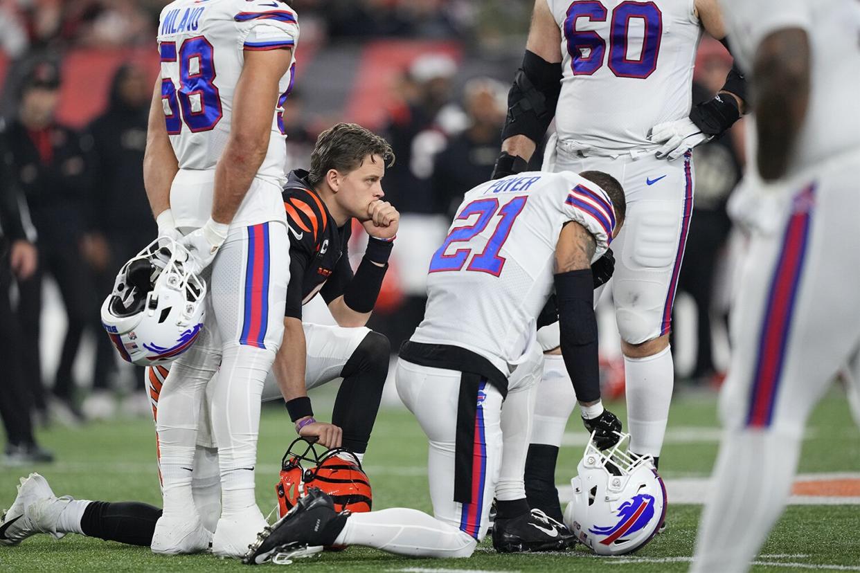 CINCINNATI, OHIO - JANUARY 02: Quarterback Joe Burrow #9 of the Cincinnati Bengals and Jordan Poyer #21 of the Buffalo Bills take a knee after Damar Hamlin #3 of the Bills collapsed following making a tackle during the first quarter at Paycor Stadium on January 02, 2023 in Cincinnati, Ohio. (Photo by Dylan Buell/Getty Images)