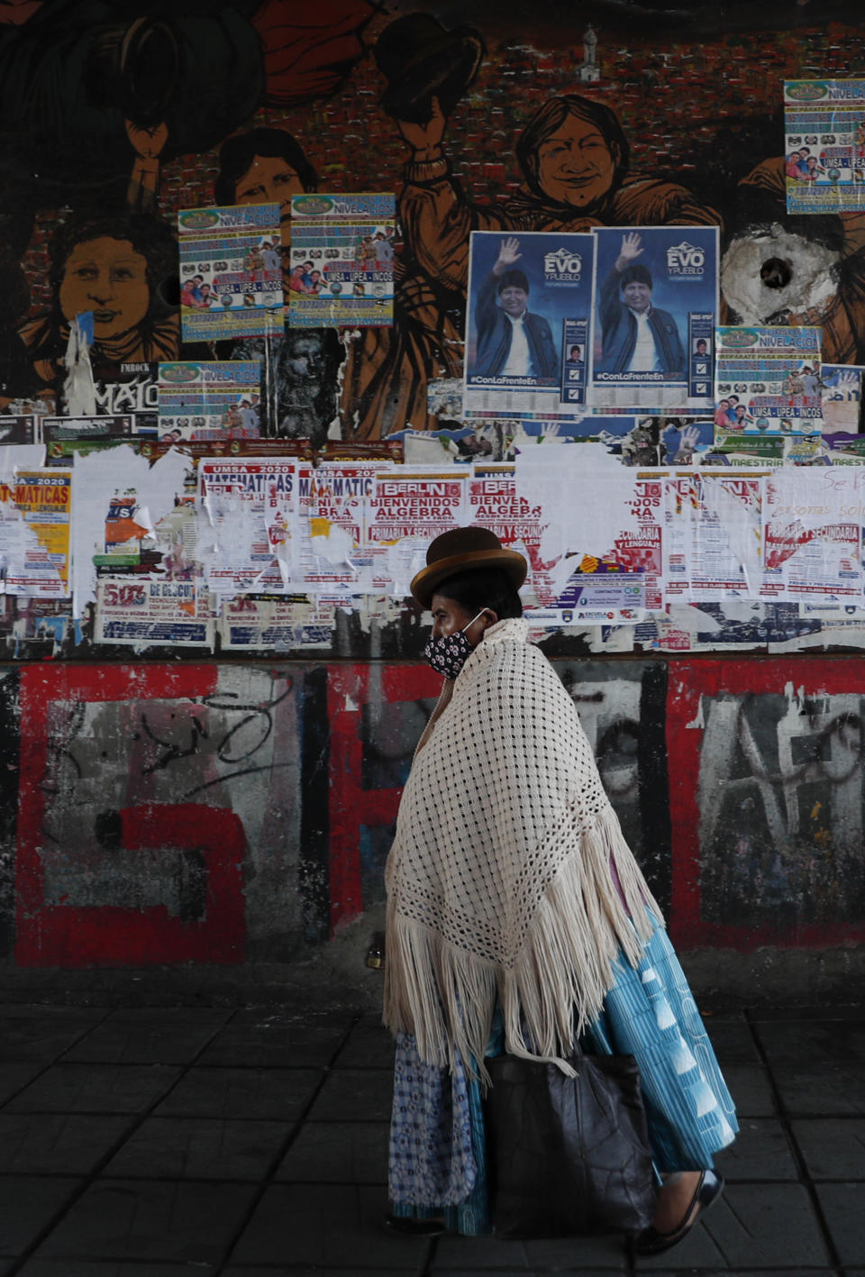 Una mujer pasa junto a una pared llena de carteles de propaganda electoral en El Alto, Bolivia, el jueves 15 de octubre de 2020. Bolivia celebrará elecciones generales el domingo 18 de octubre. (AP Foto/Juan Karita)