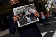 Un hombre sostiene un periódico en la plaza Black Lives Matter cerca de la Casa Blanca, después del día de las elecciones en Washington.