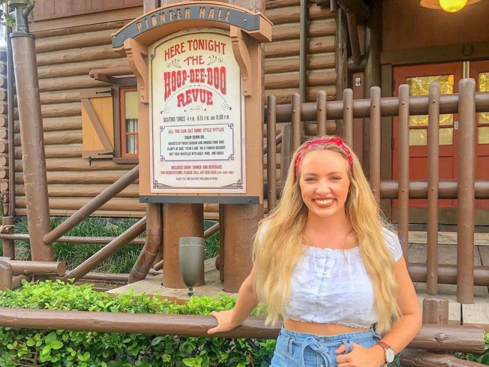kayleigh posing in front of the sign for hoopdeedoo revue at disney world