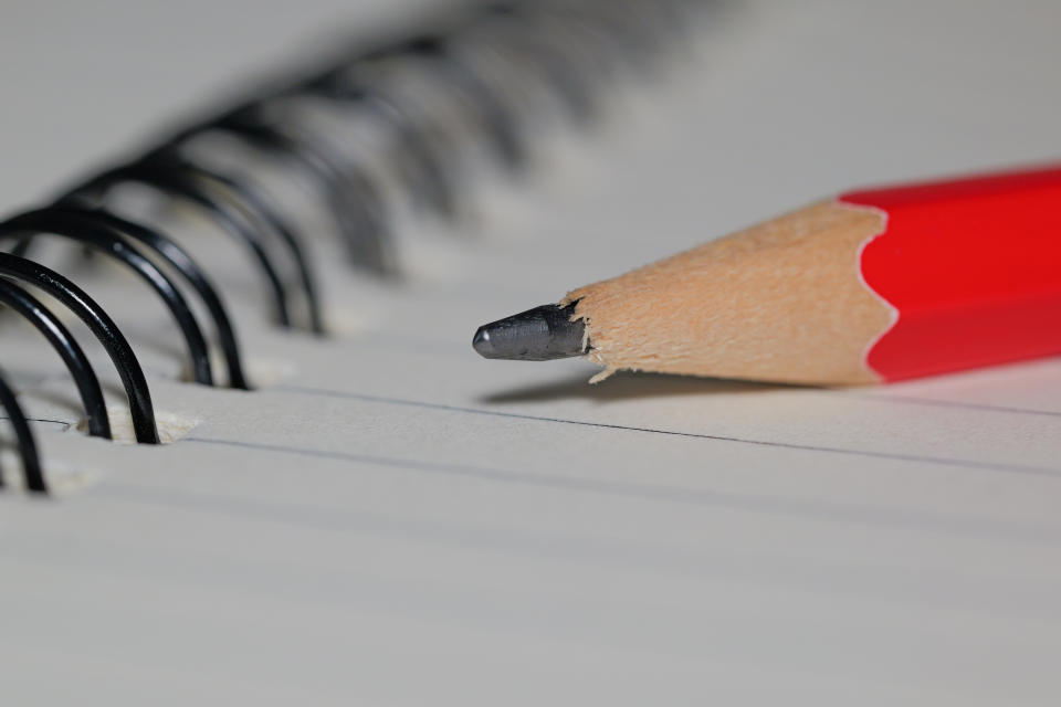 Close up on the tip of a pencil sitting on a notepad