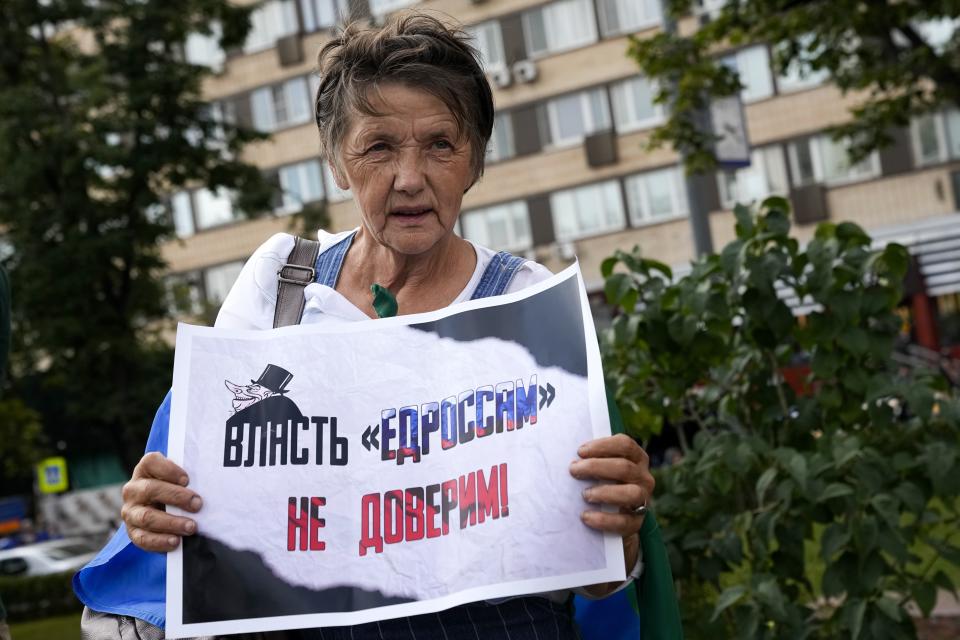 FILE - In this Aug. 14, 2021, file photo, an elderly opposition activist with a poster reading "we do not trust the power of United Russia party" attends an anti-vaccination protest in the center of Moscow, Russia. Imprisoned Russian opposition leader Navalny and his embattled allies won't be running in the Sept. 19 parliamentary election, but they still hope to challenge the ruling United Russia party with their strategy known as Smart Voting. (AP Photo/Alexander Zemlianichenko, File)