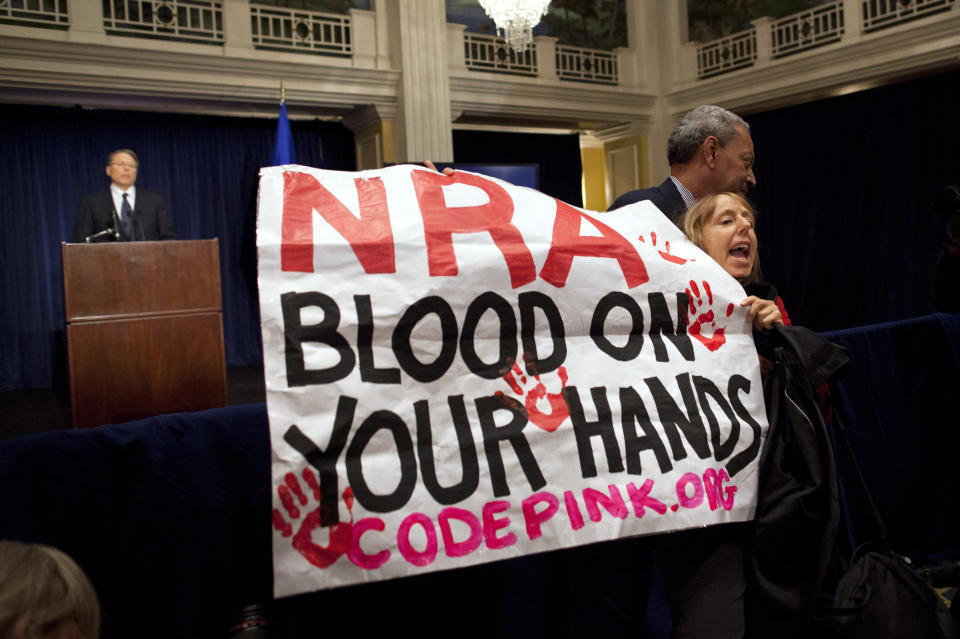 FILE - In this Dec. 21, 2012, file photo, activist Medea Benjamin, of Code Pink, is led away by security as she protests during a statement by National Rifle Association executive vice president Wayne LaPierre, left, during a news conference in response to the Connecticut school shooting in Washington. In the latest national furor over mass killings, the tremendous political power of the NRA is likely to stymie any major changes to gun laws. The man behind the organization is LaPierre, the public face of the Second Amendment with his bombastic defense of guns, freedom and country in the aftermath of every mass shooting. (AP Photo/ Evan Vucci, File)