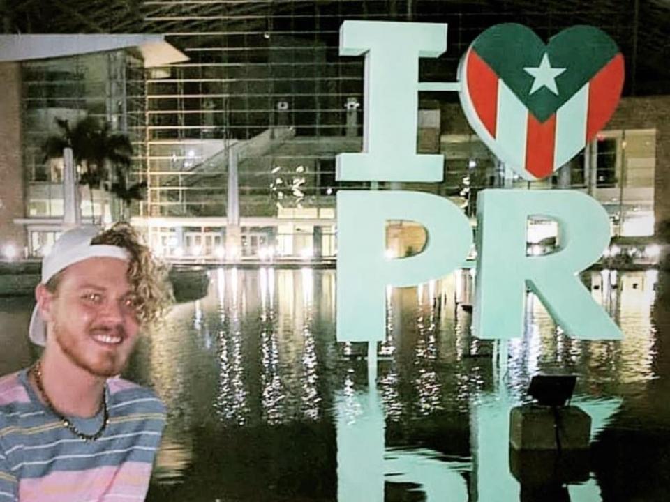 Man sitting by water with "I heart PR" sign.