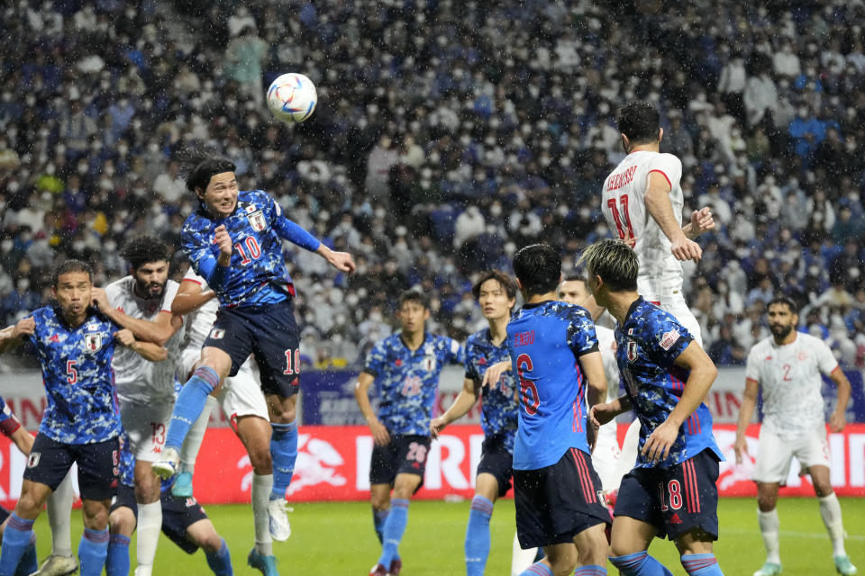 Takumi Minamino of Japan, left, and Tunisia's Taha Yassine Khenissi jump for the ball during the Kirin Cup soccer tournament in Suita, west Japan, Tuesday, June 14, 2022. (AP Photo/Eugene Hoshiko)