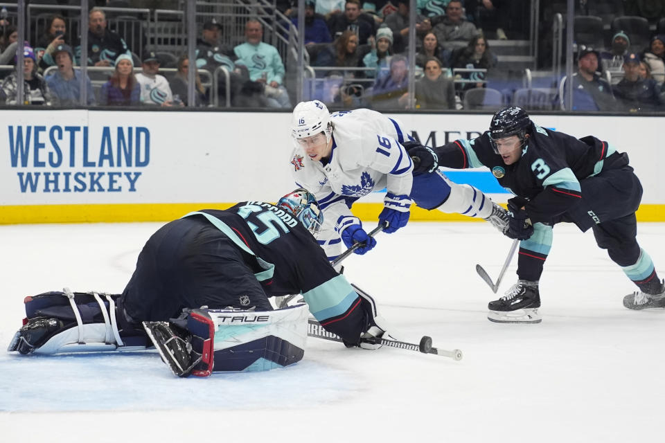 Seattle Kraken goaltender Joey Daccord (35) blocks a shot by Toronto Maple Leafs right wing Mitchell Marner (16) as Kraken defenseman Will Borgen (3) looks on during the second period of an NHL hockey game Sunday, Jan. 21, 2024, in Seattle. (AP Photo/Lindsey Wasson)