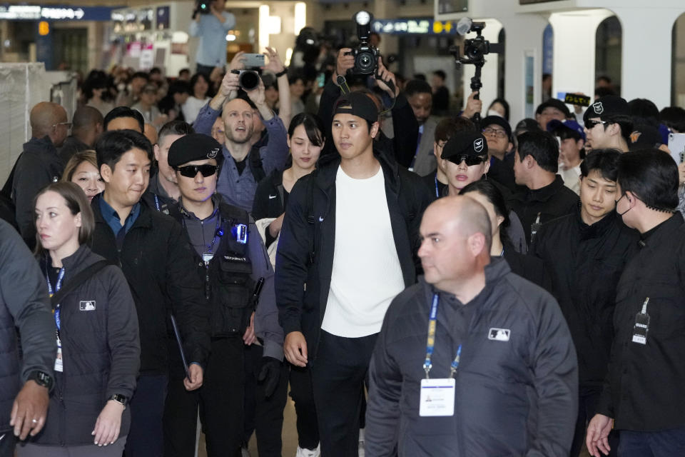 Los Angeles Dodgers Shohei Ohtani, center, walks with his wife Mamiko Tanaka, center left, through a terminal during the baseball team's arrival at Incheon International Airport, Friday, March 15, 2024, in Incheon, South Korea, ahead of the team's baseball series against the San Diego Padres. (AP Photo/Ahn Young-joon)