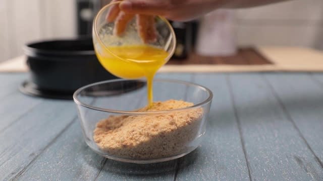 Pouring melted butter into biscuit crumbs