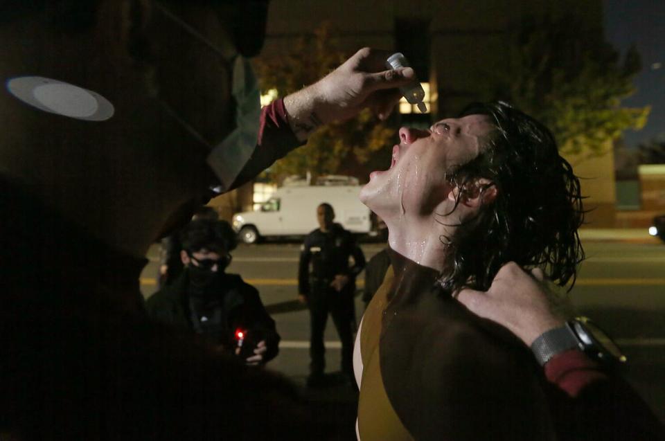 A supporter of Palestine gets his eyes washed out after being maced by a supporter of Israel outside The Museum of Tolerance