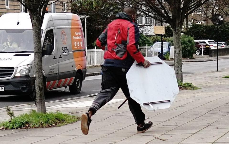 Photos from the scene show a man in red and black running in front of a white van with the stop sign after managing to remove it