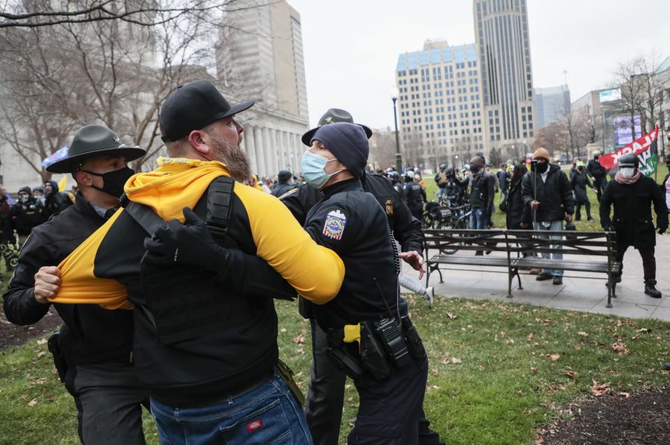 Law enforcement officers restrain a member of the Proud Boys as a fight breaks out during a “Stop the Steal” rally on Jan. 6, 2021 at the Ohio Statehouse in Columbus. Hundreds of supporters of President Donald Trump, including members of the Proud Boys came to the Statehouse to protest the congressional certification of Democratic President-Elect Joe Biden who defeated incumbent Republican President Donald Trump during the November 2020 elections and whose victory was certified by the Electoral College in December 2020.