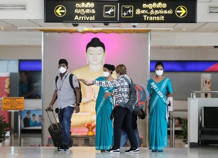 Foto del viernes de funcionarias del aeropuerto de Bandaranaike usando máscaras mientras guían a los turistas en Katunayake, Sri Lanka