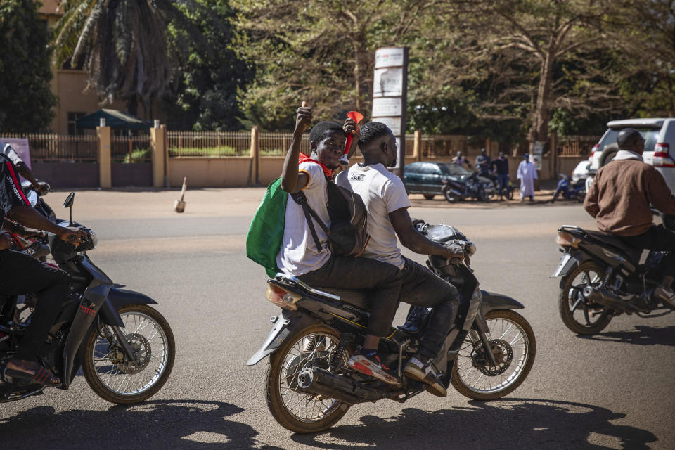 People cheer in support of putschist soldiers near the national television station in Ouagadougou, Monday Jan. 24, 2022. Two mutinous soldiers told The Associated Press that Burkina Faso’s President Roch Marc Christian Kabore is being held by the rebellious soldiers. Gunshots rang late Sunday night near the president’s residence and in the early hours of Monday a battle took place at the presidential palace while a helicopter flew overhead. (AP Photo/Sophie Garcia)