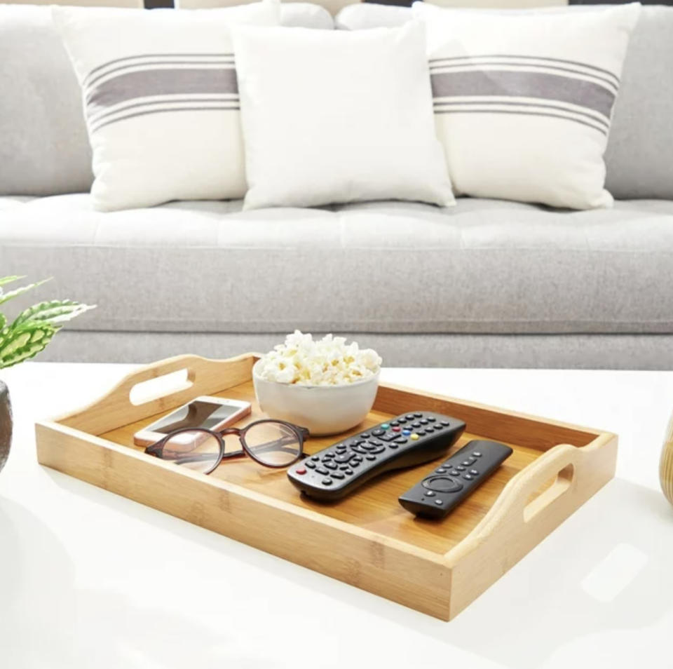 the tray with popcorn, remotes, glasses, and phone