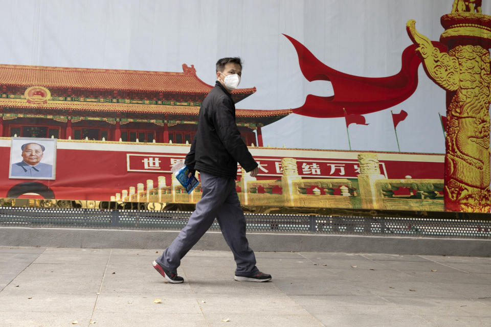 A resident wearing a mask against coronavirus walks past government propaganda poster featuring Tiananmen Gate in Wuhan in central China's Hubei province Thursday, April 16, 2020. (AP Photo/Ng Han Guan)
