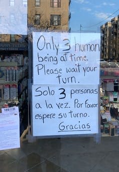 A sign in a storefront requests only three customers enter at a time.