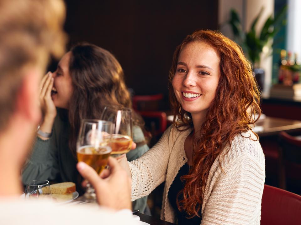 redheaded woman toasting wine at dinner