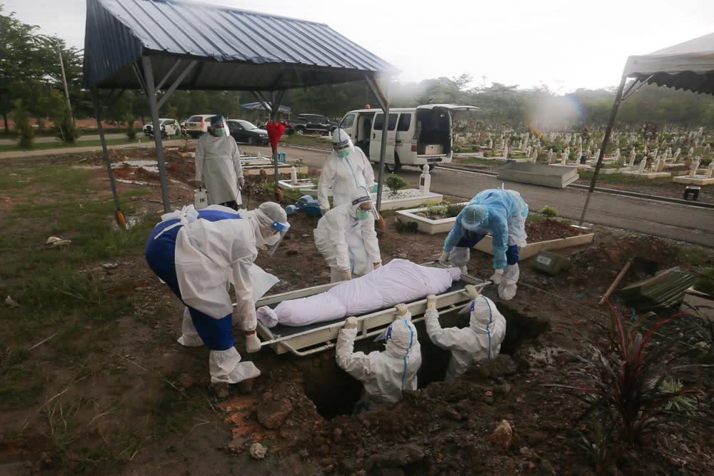 Workers wearing protective suits bury a Covid-19 victim at a cemetery in Shah Alam May 18, 2021. — Picture by Yusof Mat Isa