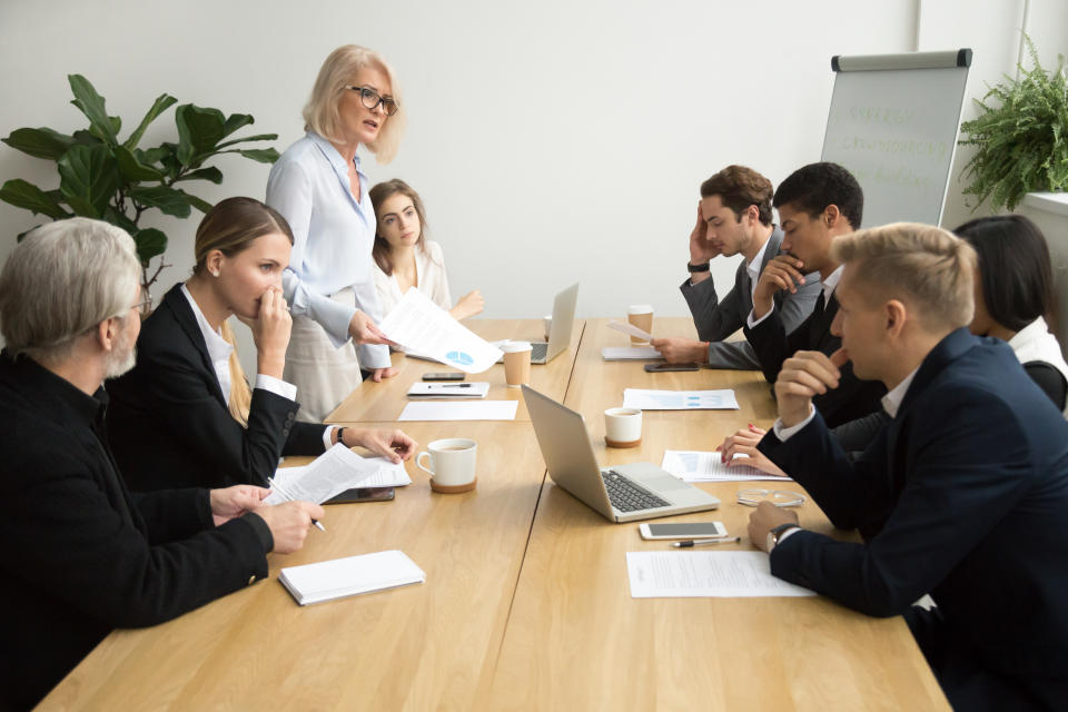 Dissatisfied boss scolding employees for bad work at group meeting, 