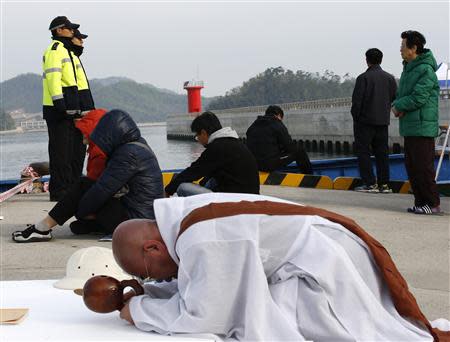 Family members of missing passengers onboard South Korean ferry Sewol, which capsized on Wednesday, look at the sea as a Buddhist monk prays for the missing people at a port in Jindo April 22, 2014. REUTERS/Kim Kyung-Hoon