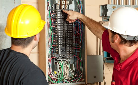 Two electricians replacing a circuit breaker